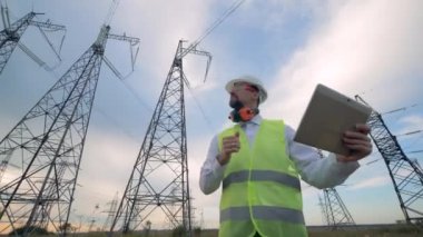 Güç hattı yakınındaki tablet ile çalışan elektrikçi mühendisi.