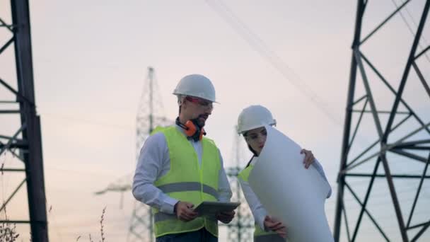 Працівники лінії електропередач дивляться на схему на папері. 4-кілометровий . — стокове відео