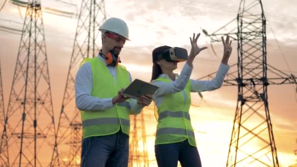 Un ingeniero masculino escribe en una tableta, mientras que una mujer usa gafas VR. 4K . — Vídeo de stock