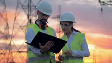 Profesyonel elektrik güç satırı yakınlarında çalışırken bir dizüstü bilgisayarı kullanıyor.