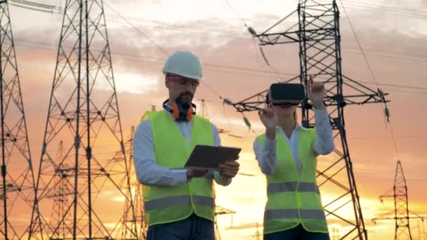 Ingenieur in de Vr-bril werkt op de bouwplaats, terwijl een elektricien typen op een Tablet PC. — Stockvideo