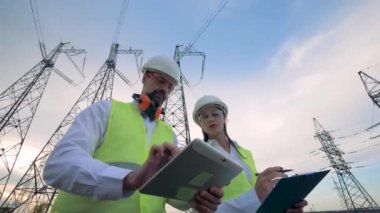 Mühendisleri kendi iş yerinde bir iletim hatları tartışmak. Profesyonel elektrik inşaat planı tartışmak.
