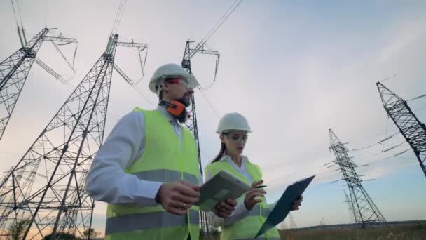 Eletricistas profissionais trabalham juntos perto de linhas de transmissão. 4K . — Vídeo de Stock