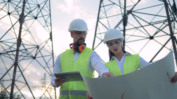 Os eletricistas verificam o trabalho das linhas de energia. As pessoas discutem um plano, verificando informações em um tablet . — Vídeo de Stock