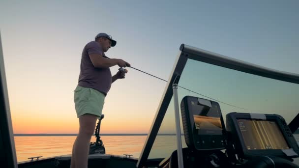 Fisherman is standing in an equipped boat and catching fish — Stock Video