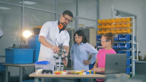 Los niños están observando un robot en funcionamiento en manos de un trabajador de laboratorio — Vídeos de Stock