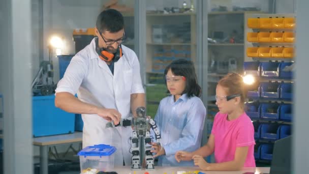 I bambini piccoli e uno specialista della ricerca stanno muovendo gli arti dei robot — Video Stock