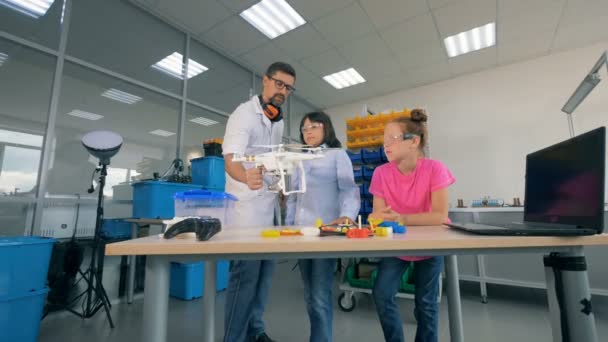Lab assistant is demonstrating a quadcopter to teenagers — Stock Video