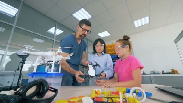 Teenagers and a male instructor are observing a quadcopter — Stock Video