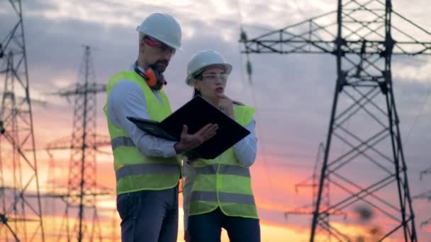 Électriciens professionnels discutant du plan de construction près des lignes de transmission, gros plan . — Video