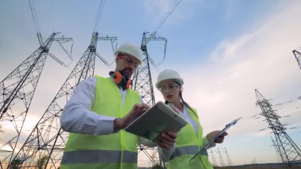 A táblaszámítógép elektromos alállomás, alállomás energia, elektromos alállomás közelében dolgozó mérnökök. — Stock videók