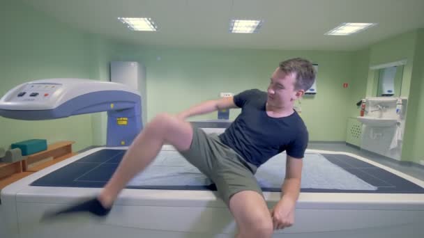 Paciente do sexo masculino deita-se em uma cama de uma máquina de digitalização em uma clínica. 4K . — Vídeo de Stock