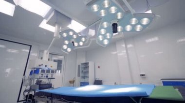Ameliyathane yatakta yukarıda asılı iki cerrahi lambalar. Parlak ameliyat odası modern ekipmanla donatılmış.
