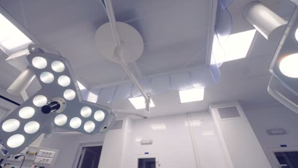 El doctor está juntando dos lámparas quirúrgicas en una sala médica. — Vídeos de Stock