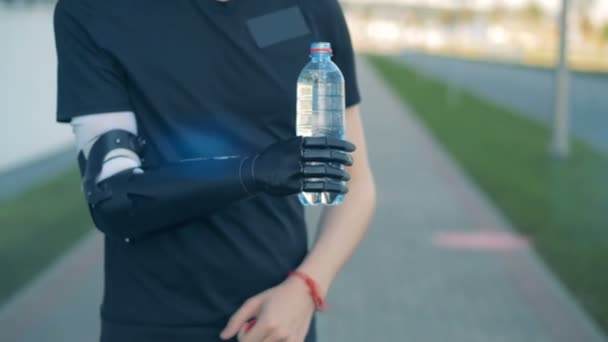 Fysiek uitgedaagd man is drinkwater met zijn futuristische bionic hand. — Stockvideo