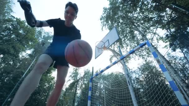 一个仿生机器人手臂的青少年正在玩弄一个球, 并试图击中篮 — 图库视频影像