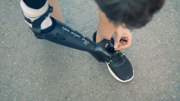 Los cordones de las zapatillas están siendo atados por un hombre con una mano protésica — Vídeos de Stock