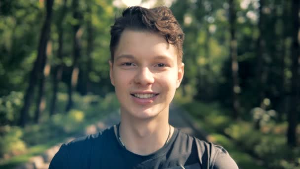 Gros plan d'un adolescent garçon souriant tout en restant debout à l'extérieur — Video