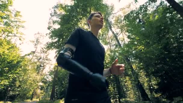 Un hombre con un brazo artificial corre por el callejón. Concepto futurista de cyborg humano . — Vídeos de Stock