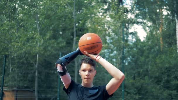 Lanzamiento en cámara lenta de una pelota de basket por un adolescente con una mano biónica robótica — Vídeo de stock