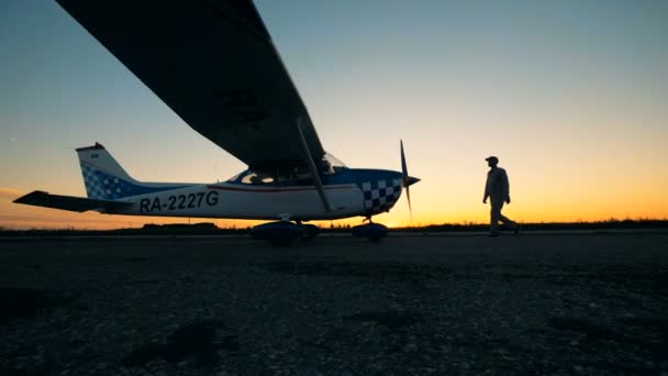 Pessoa de pé perto de seu avião em um fundo por do sol. Conceito de aviação pequena . — Vídeo de Stock