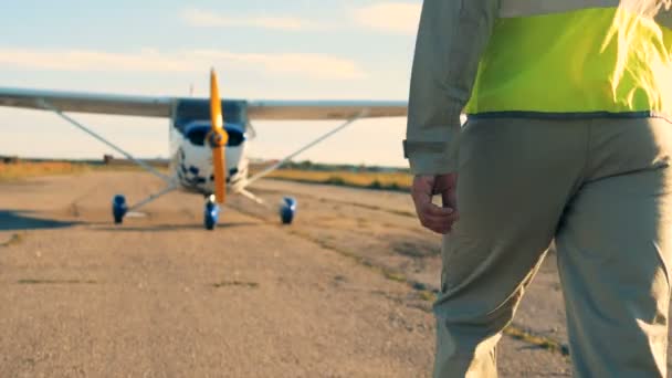 Piloto en una pista, vista trasera. Piloto profesional llegando a su avión, caminando en un aeródromo . — Vídeos de Stock