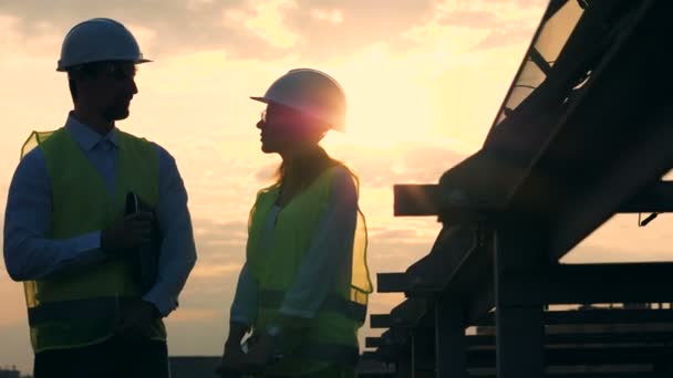 日落景观与两名员工在一个太阳能电池附近交谈 — 图库视频影像