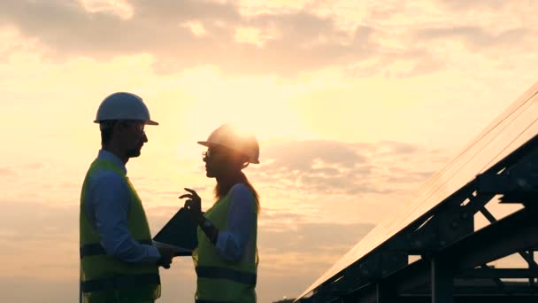 Diskussionsprocess av en manlig och en kvinnlig solar konstruktörer under solnedgången. — Stockvideo