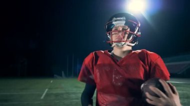 Amerikan futbolu için bir top elinde tutan bir adam girer. 4k.