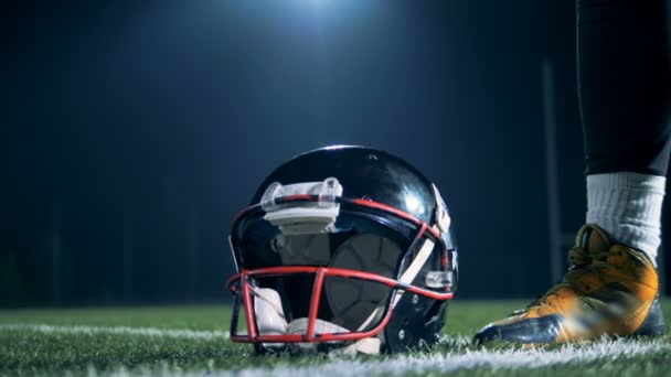 Sportsman, american football player picks up a helmet from a grass at a stadium. — Stock Footage Sportsman, american football player picks up a helmet from a grass at a stadium. Stock Footage