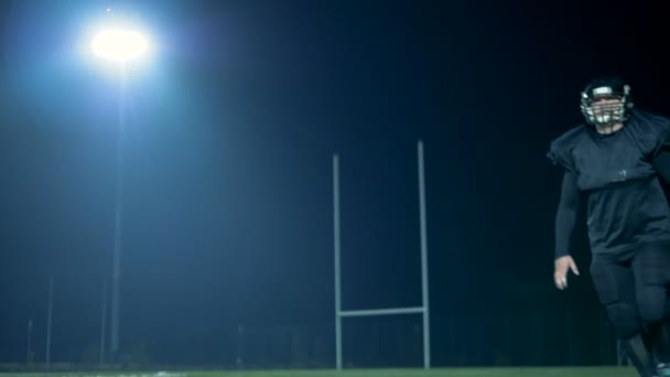 Il calciatore americano prende un pallone volante e guarda una macchina fotografica. 4K . — Video Stock