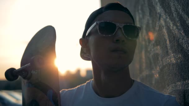 一个年轻的溜冰者在日落背景下滑板的肖像. — 图库视频影像