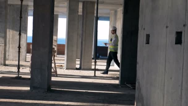 Строительная площадка и мужчина-инспектор, идущий по ней — стоковое видео