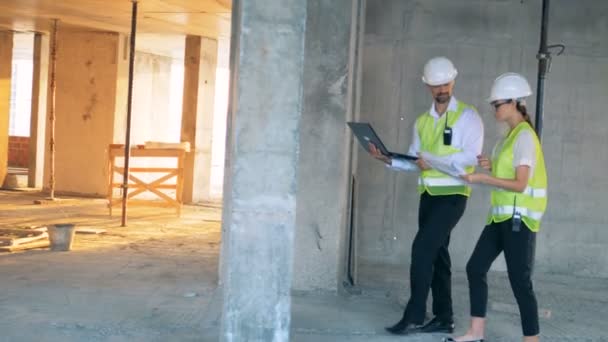 Dos ingenieros están caminando a lo largo del sitio de construcción . — Vídeos de Stock