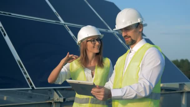 Proces van twee constructeurs langs de solar batterij en hun beraadslaging wandelen — Stockvideo