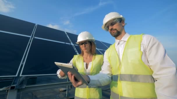 Zwei Solarspezialisten gehen und bedienen während des Gesprächs ihr Tablet — Stockvideo