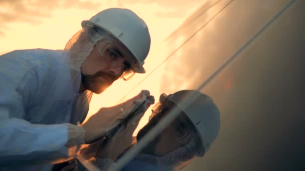 Primer plano de la superficie reflectante de una batería solar que se limpia por un trabajador masculino — Vídeo de stock