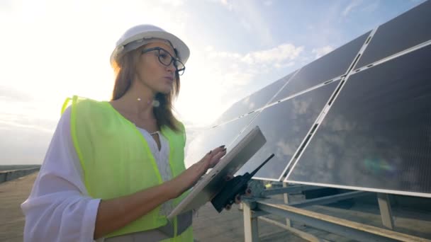 Női mérnök-villanyszerelő áll, a tetőn, dolgozik egy tabletta és a gazdaság egy walkie-talkie. — Stock videók