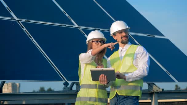 Dwóch inżynierów pracujących w pobliżu paneli słonecznych na dachu budynku. Pojęcie energii odnawialnej. — Wideo stockowe