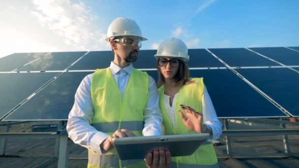 Dois trabalhadores estão em painéis solares de fundo, de perto . — Vídeo de Stock