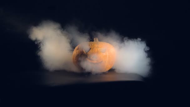 Calabaza de halloween naranja en una mesa rodeada de humo, de cerca . — Vídeo de stock