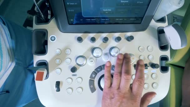 Αρσενικό ο γιατρός ωθεί τα κουμπιά σε μια συσκευή υπερήχων, το top view. — Αρχείο Βίντεο