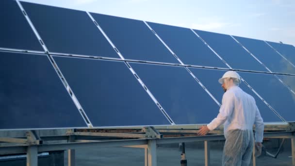 Un hombre revisando paneles solares. Un ingeniero mira las baterías solares y las toca . — Vídeo de stock