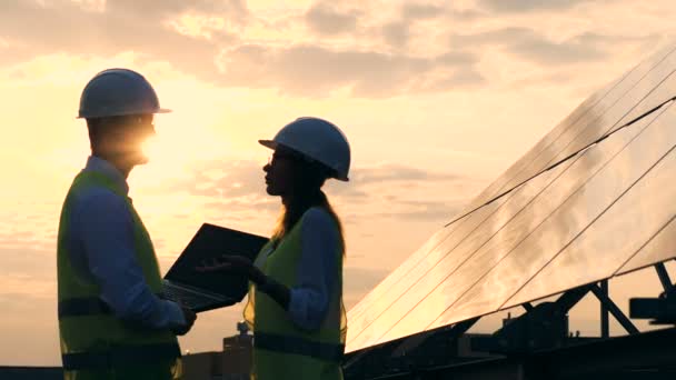 Arbetstagare som pratar på en solnedgång bakgrund, sidovy. — Stockvideo