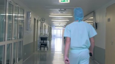 Bir klinik salonunda yürüyen bir adam. Kişi Doktor Tekdüzen bir hastane binada yürüyor.