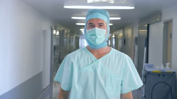 Um cirurgião numa clínica. Cirurgião masculino guarda máscara de proteção enquanto olha para uma câmera . — Vídeo de Stock