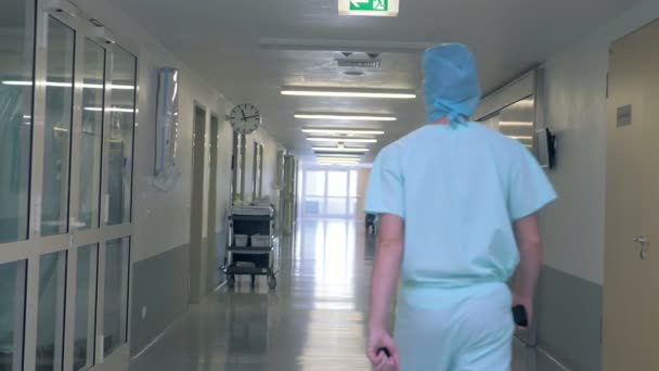 Ένας άνθρωπος περπατώντας σε μια αίθουσα κλινική. Πρόσωπο σε γιατρό ομοιόμορφη βόλτες σε ένα κτίριο του νοσοκομείου. — Αρχείο Βίντεο