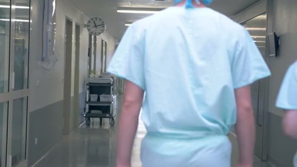 A klinika épülete az emberek. Férfi és nő a kórházban egy üres folyosón, séta. — Stock videók
