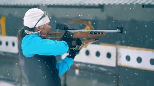 Female athlete aims with a rifle, then looks at a camera. 4K — Stock Video