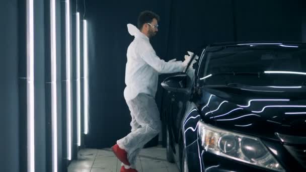 Boldog munkás táncok közben fényezési egy autó, zár-megjelöl. — Stock videók